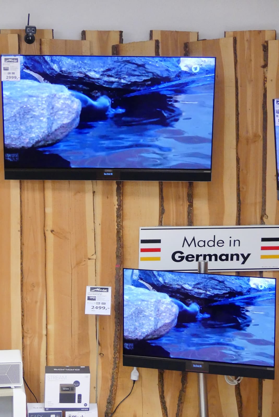 Zwei Metz-Fernseher an der Holzwand, dazwischen ein Schild Made in Germany