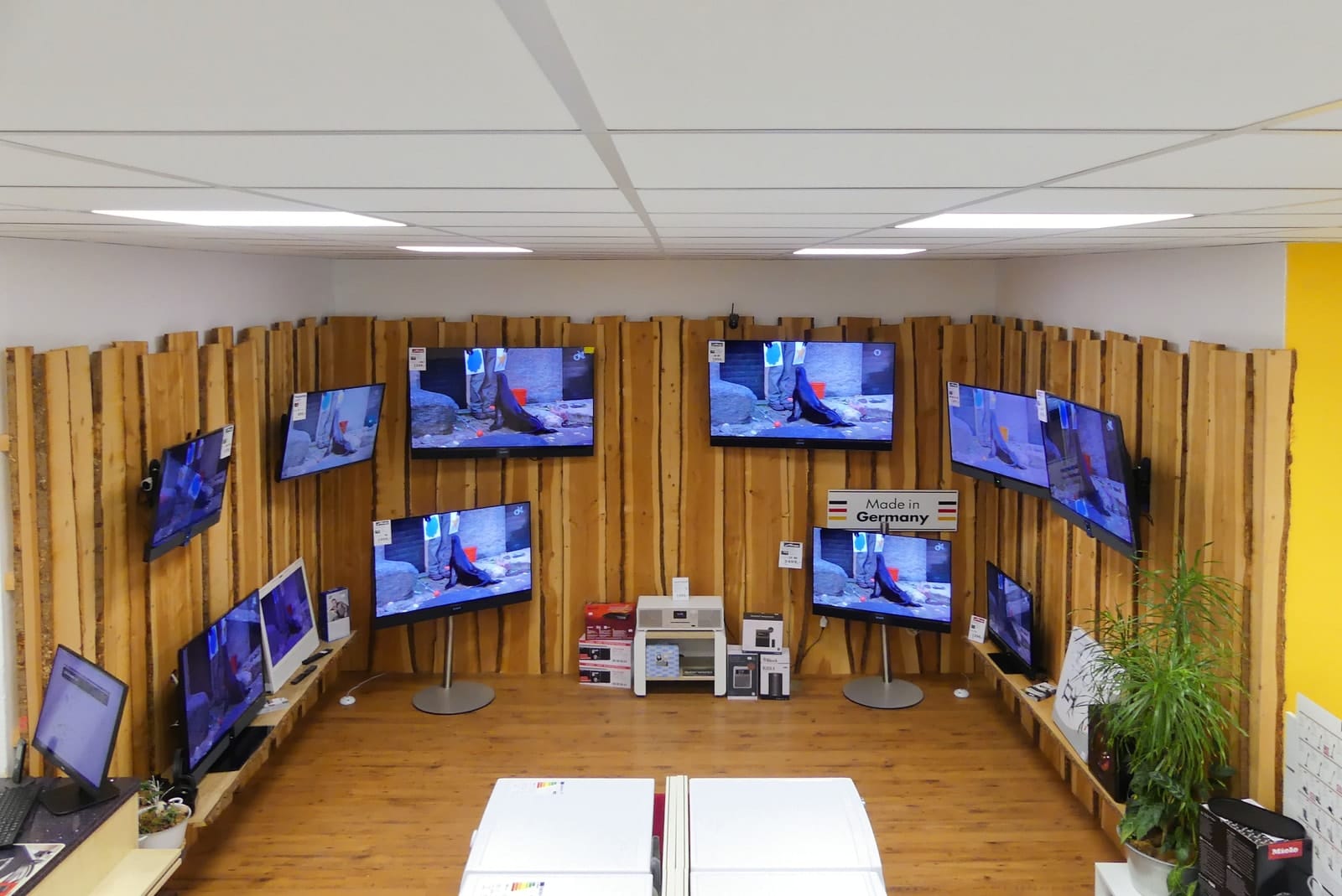 Fernsehstudio mit vielen Flachbildfernsehern an einer Wand aus rohen Holzbrettern